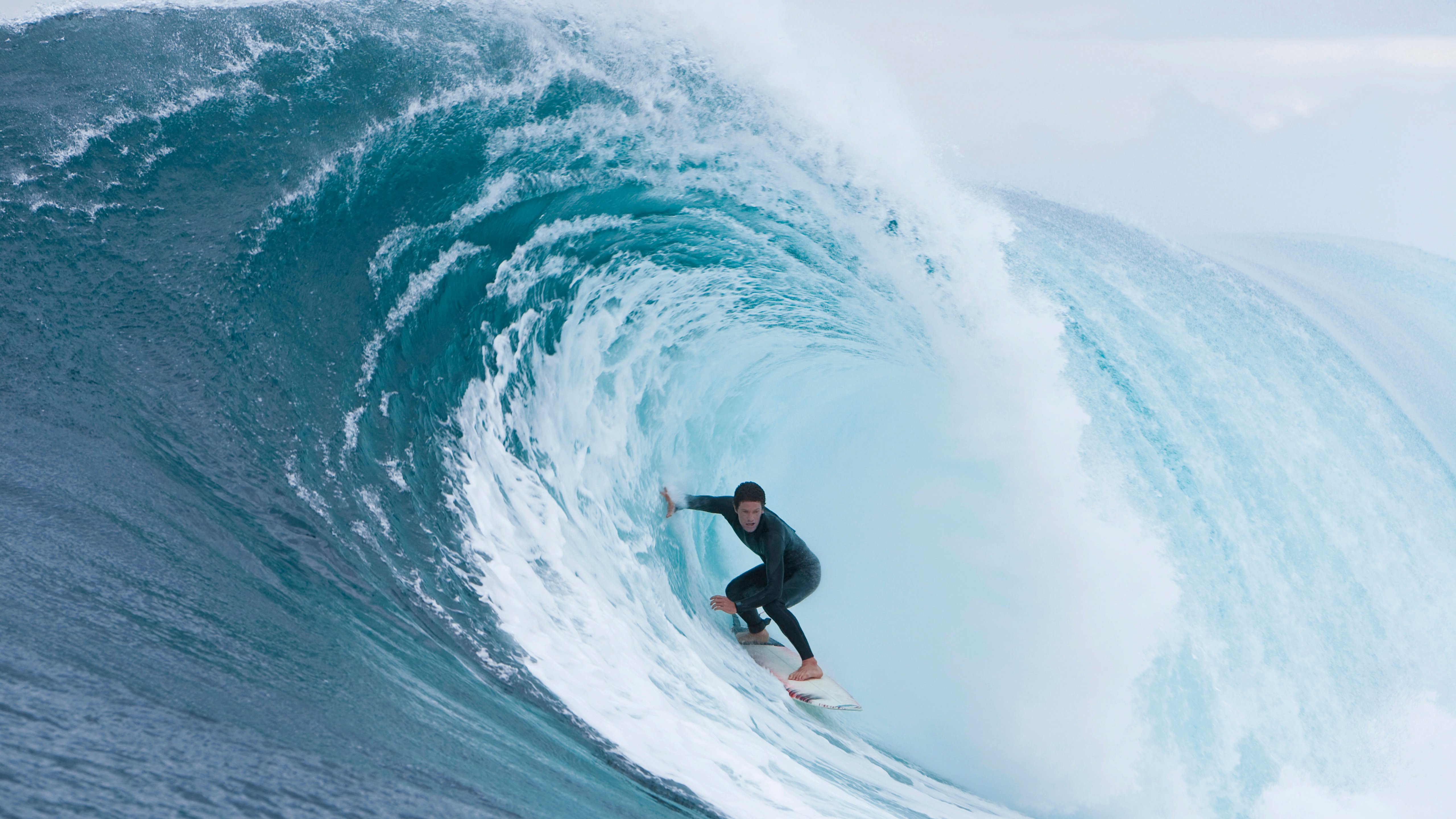 Person riding surfboard inside curl of wave