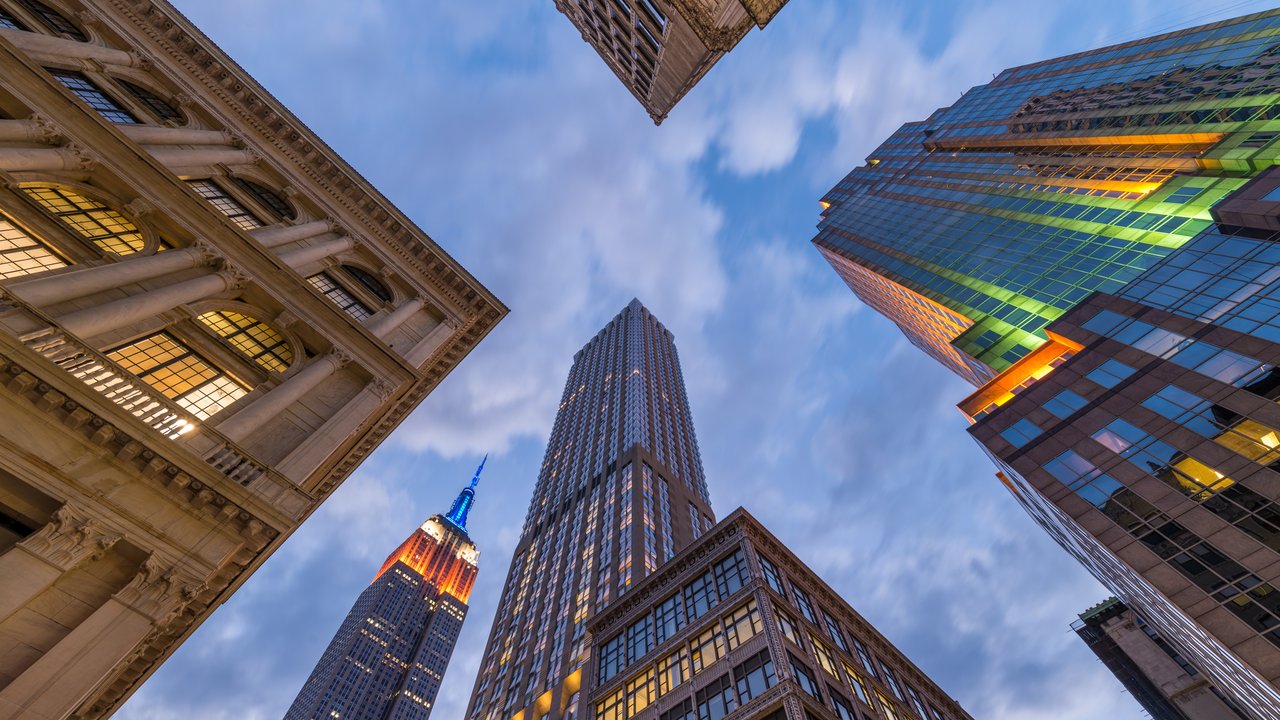 View of tall buildings including the Empire State Building against a cloudy sky.